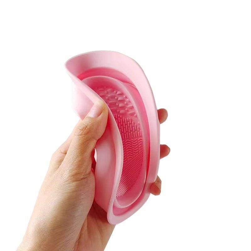 Accesoriu din silicon roz, flexibil și pliabil, ideal pentru curățarea eficientă a pensulelor și bureților de machiaj.
