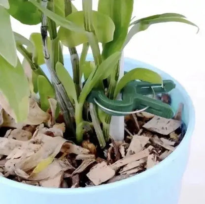 Clips pentru plante fixat pe un suport într-un ghiveci, oferind stabilitate tulpinilor. Perfect pentru grădinărit și îngrijirea plantelor.