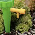 Prim-plan al picuratorului pentru plante, verde, cu robinet galben reglabil, eliberând apă picătură cu picătură pentru hidratarea optimă a solului.