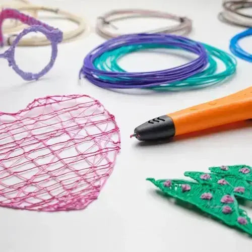 Diverse creații artistice realizate cu creion 3D și filamente PLA colorate, inclusiv o inimă și un brad.